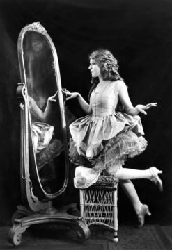Actrice en latere auteur/filmproducente Mary Pickford werpt een blik in de spiegel. Credits: Alfred Cheney Johnston, 1920.