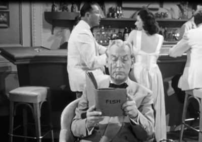 Emmett Vogan als Professor Martin die een boek leest in de film Dangerous Money uit 1946