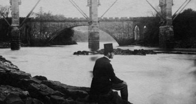 Een man alleen, zittende langs een rivier.